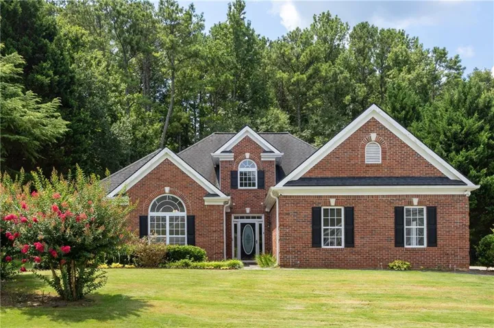 Brick exterior with a gabled roofline, featuring black shutters, white window frames, and a prominent arched entryway