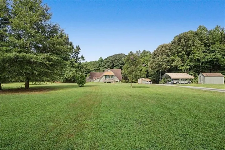 Expansive green lawn with mature trees and a detached shed