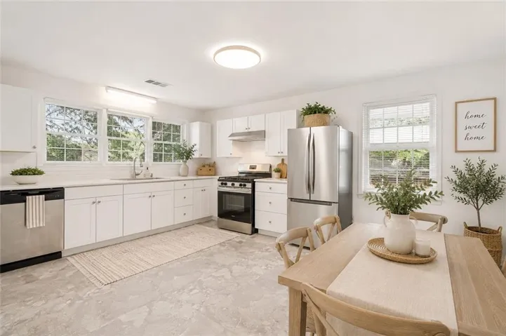 New kitchen is virtually staged. New cabinets, flooring, lighting, counters, appliances, sink, faucet and blinds