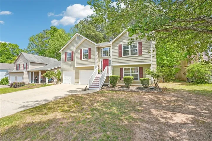 Split-level residence featuring light-colored siding, a prominent red entry door, and red window shutters