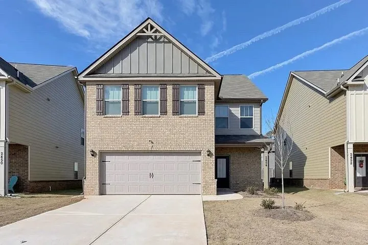 View of front of home with board and batten siding, concrete driveway, brick siding, and a garage
