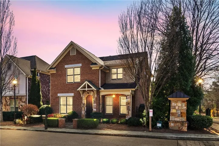 Brick facade townhome with stone accents, covered entry, and gabled roofline