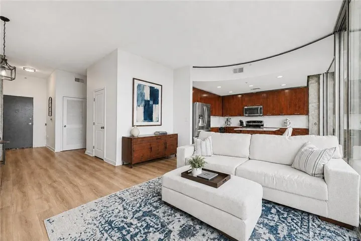 Open-concept living space featuring wood-finish flooring, recessed lighting, and a kitchen with stainless steel appliances