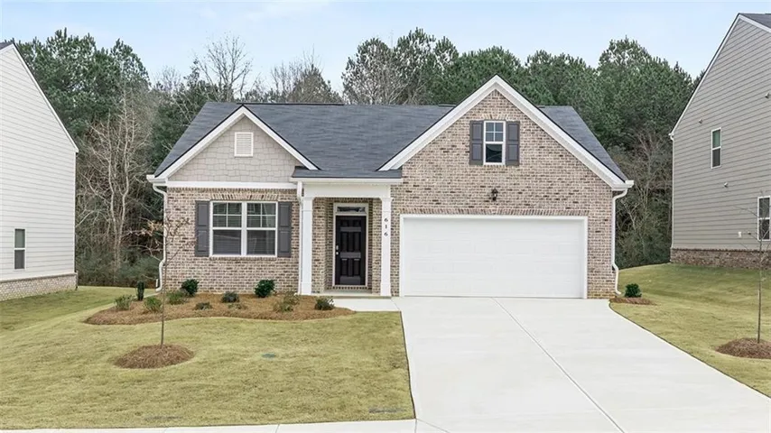 Charming brick-front home featuring a welcoming facade with peaked rooflines, multi-pane windows, and an attached two-car garage