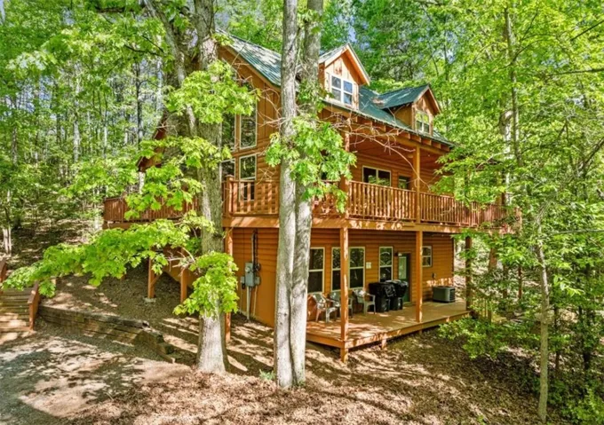 Log cabin exterior with multiple balconies and a verdant, wooded setting