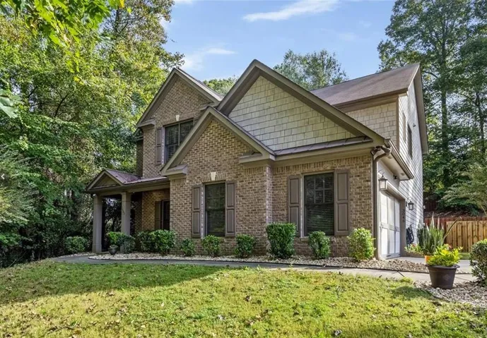 Brick and shingle exterior with gabled roofline, covered entry, and attached garage
