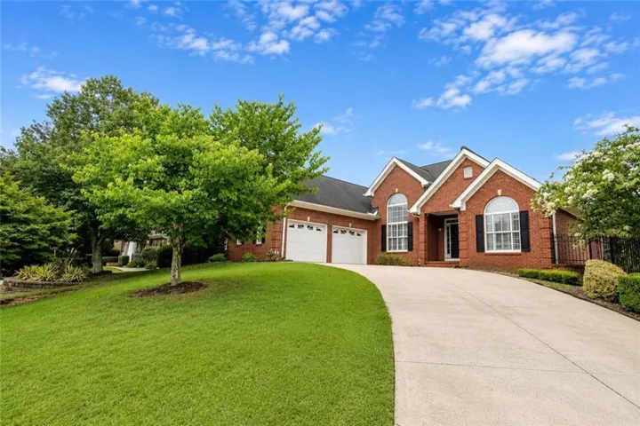 Brick exterior featuring a gabled roofline, arched windows, and a two-car garage