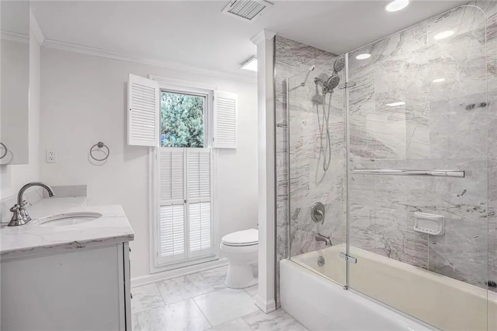 Private Bathroom with Tub, Marble Floors and Tub Surround.