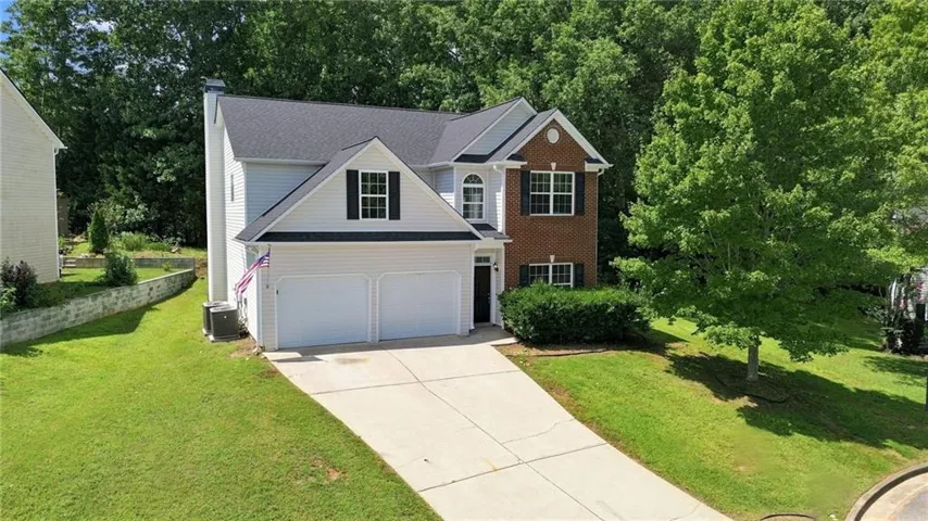 Two-story residence featuring a brick and siding exterior, a two-car garage, and a concrete driveway