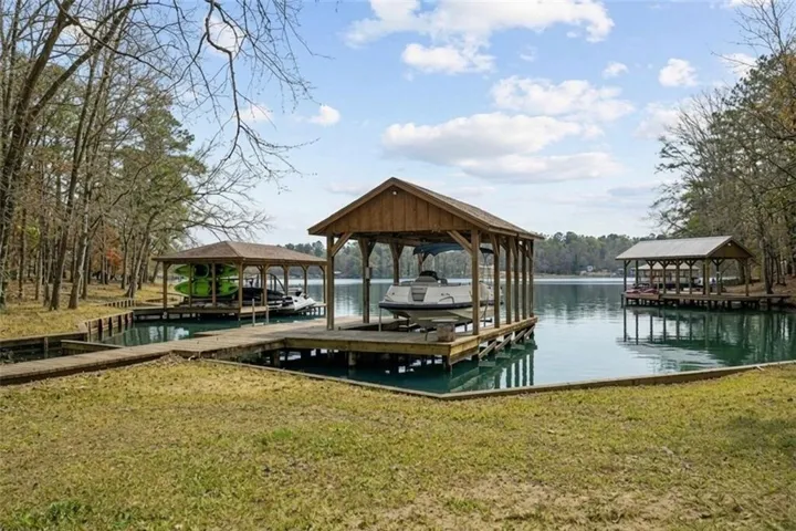 Dock featuring boat lift, a lawn, and a water view