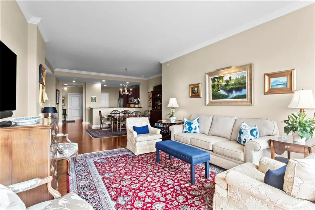 Unit 812 - Open-concept living area featuring high ceilings, crown molding, wood flooring, and a recessed dining area with chandelier lighting