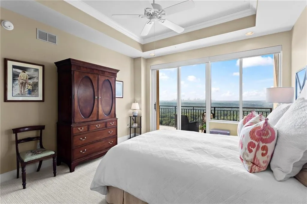Tray ceiling with recessed lighting, ceiling fan, glass door to balcony, and carpeting