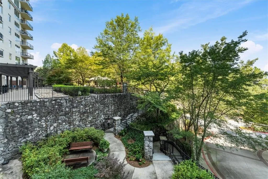 Stone retaining wall with integrated seating area, multi-level landscaping, and paved pathways