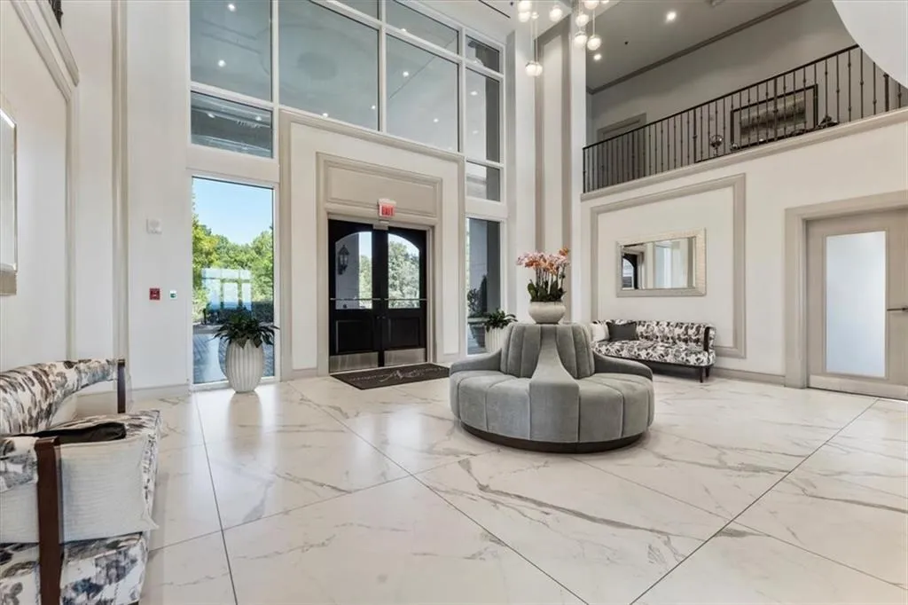 Two-story foyer featuring large format tile flooring, a second-story balcony with wrought iron railing, and a grand entrance with double doors and transom windows