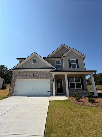 Two-story residence featuring a covered entry, attached two-car garage, brick and siding exterior, and a concrete driveway