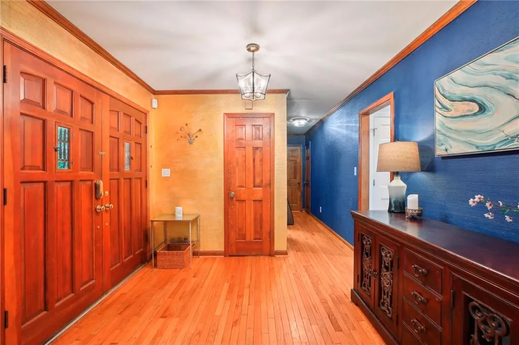 Entrance foyer with a notable chandelier, ornamental molding, and light hardwood / wood-style flooring