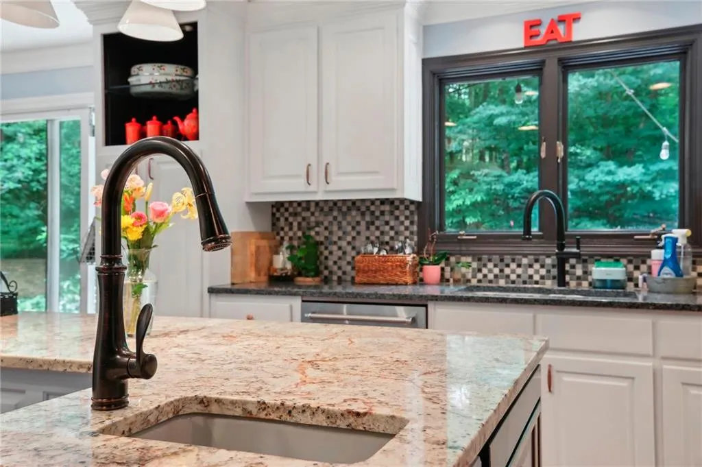 Kitchen featuring light stone counters, white cabinetry, and tasteful backsplash