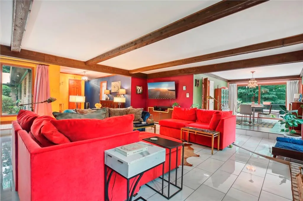 Living room featuring beamed ceiling, tile flooring, and a chandelier