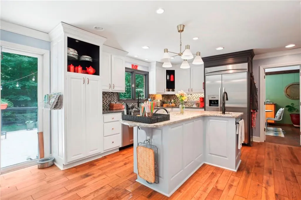 Kitchen featuring backsplash, white cabinetry, light hardwood / wood-style flooring, and pendant lighting