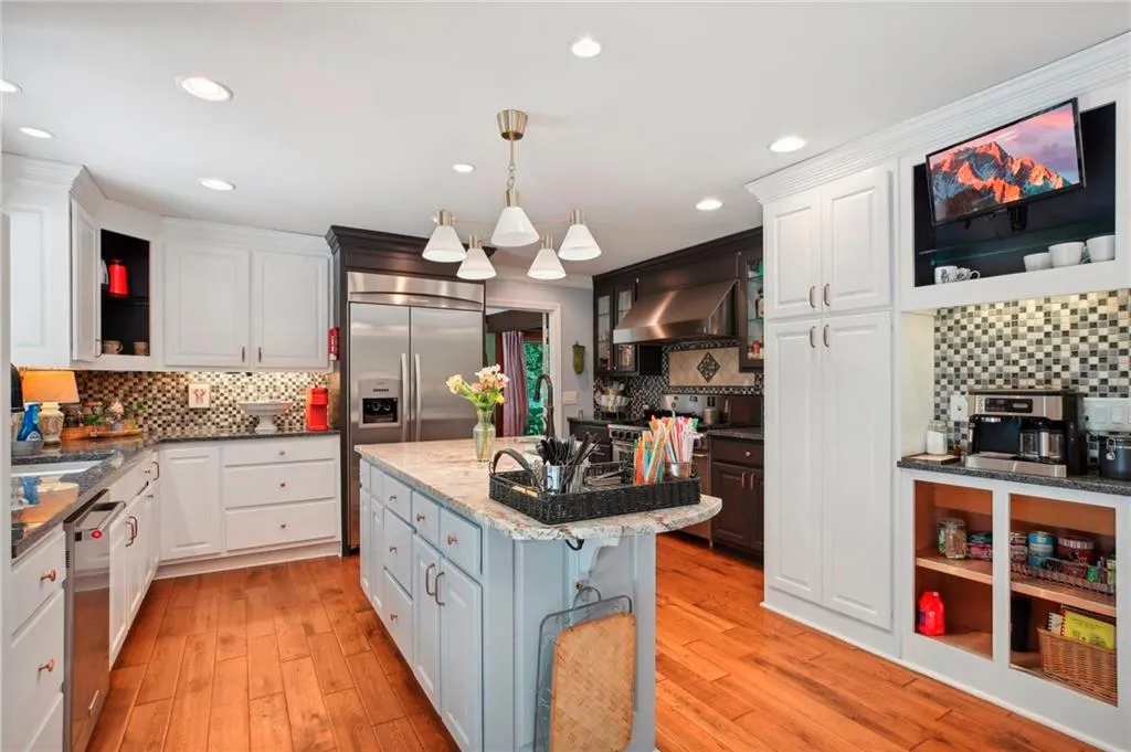 Kitchen with white cabinetry, wall chimney exhaust hood, tasteful backsplash, and a kitchen island