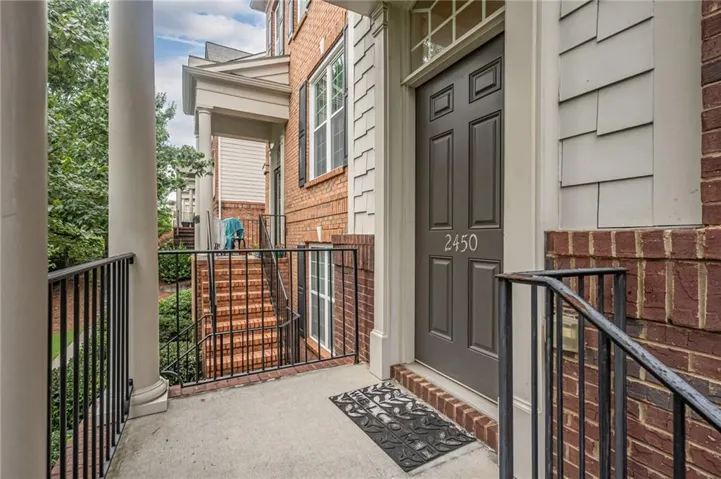 Welcoming entrance features a dark-finish front door with sidelights, black metal railings, and decorative tile flooring