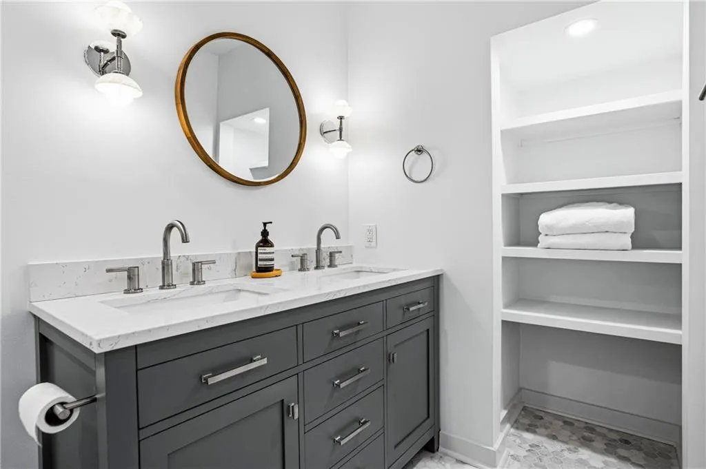 Dual vanity featuring a gray wood-finish cabinet with brushed nickel hardware, white stone countertop, and two undermount sinks