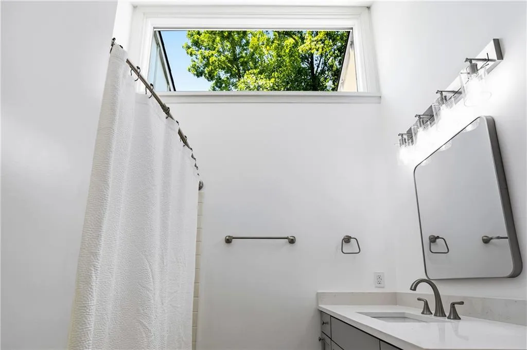 Bathroom featuring a transom window, vanity with a stone countertop, built-in rectangular sink, and contemporary hardware