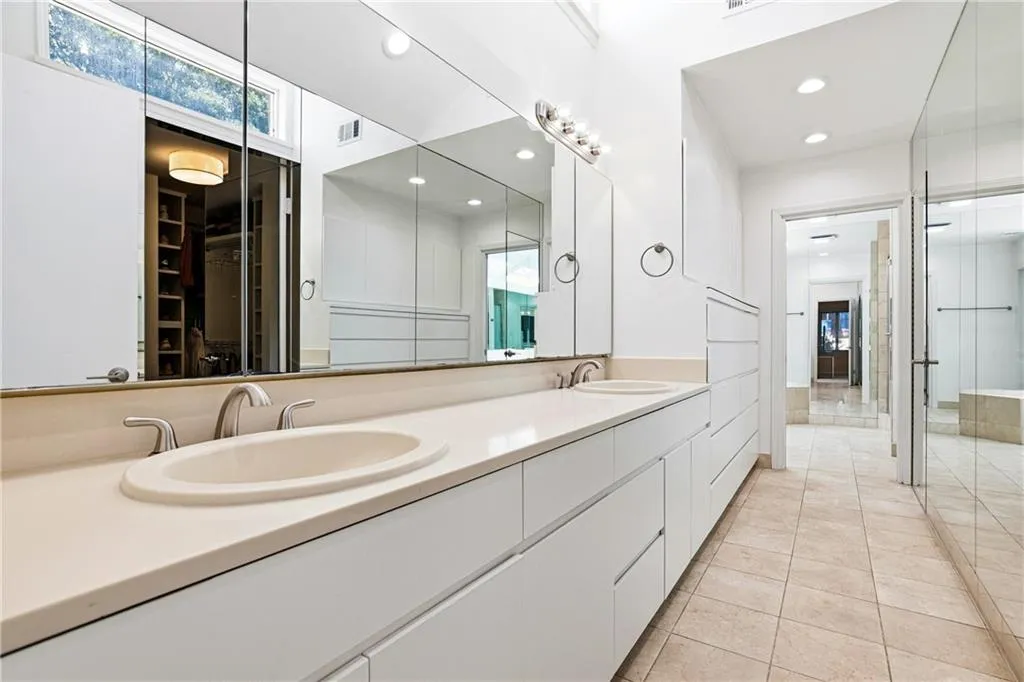 Extended vanity featuring dual integrated sinks with brushed nickel fixtures, under-counter cabinetry, and a full-width mirror