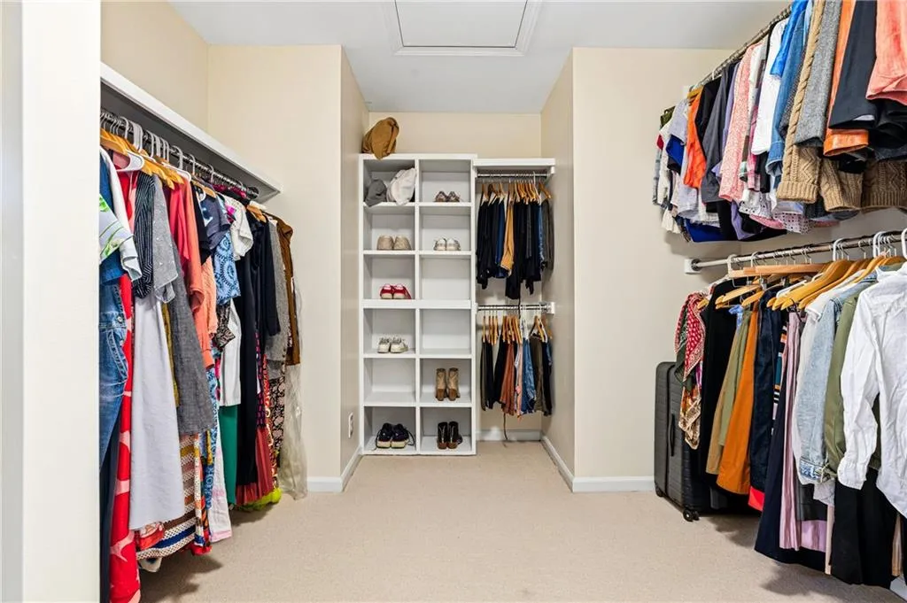 Spacious walk-in closet featuring extensive built-in shelving, multiple hanging rods, and carpet flooring