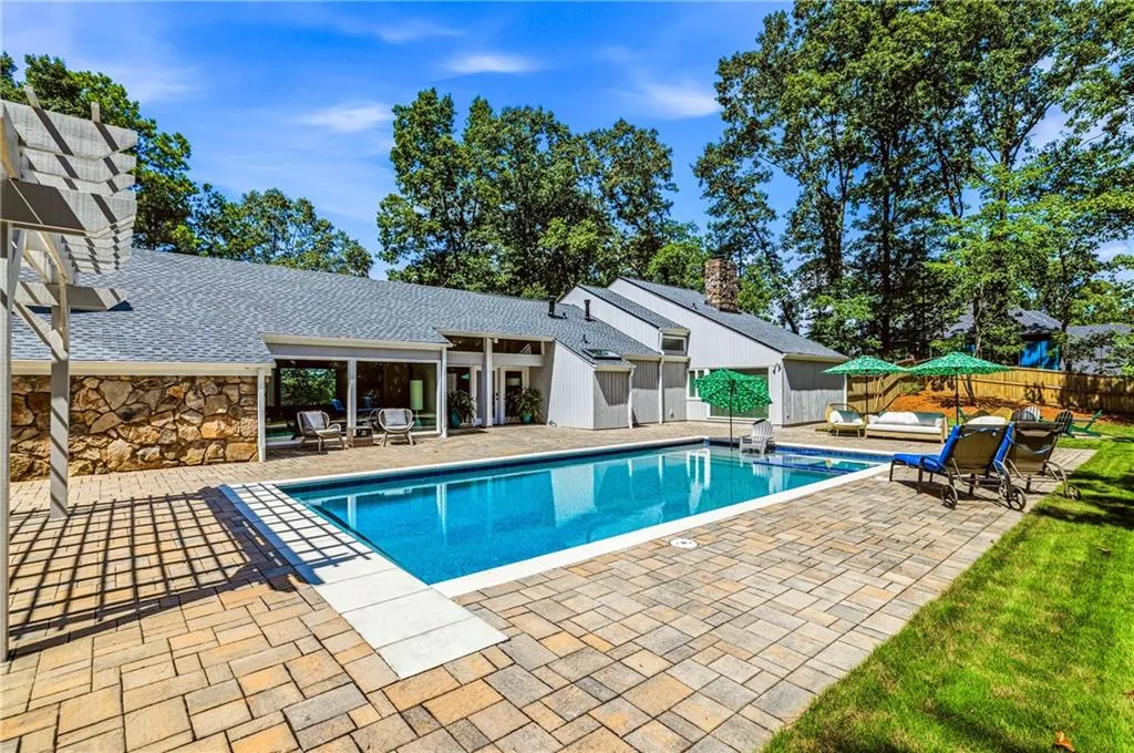Outdoor swimming pool with a surrounding paver patio and ample green space