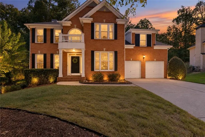 Brick exterior with white columned entry, arched window detailing, and a two-car garage
