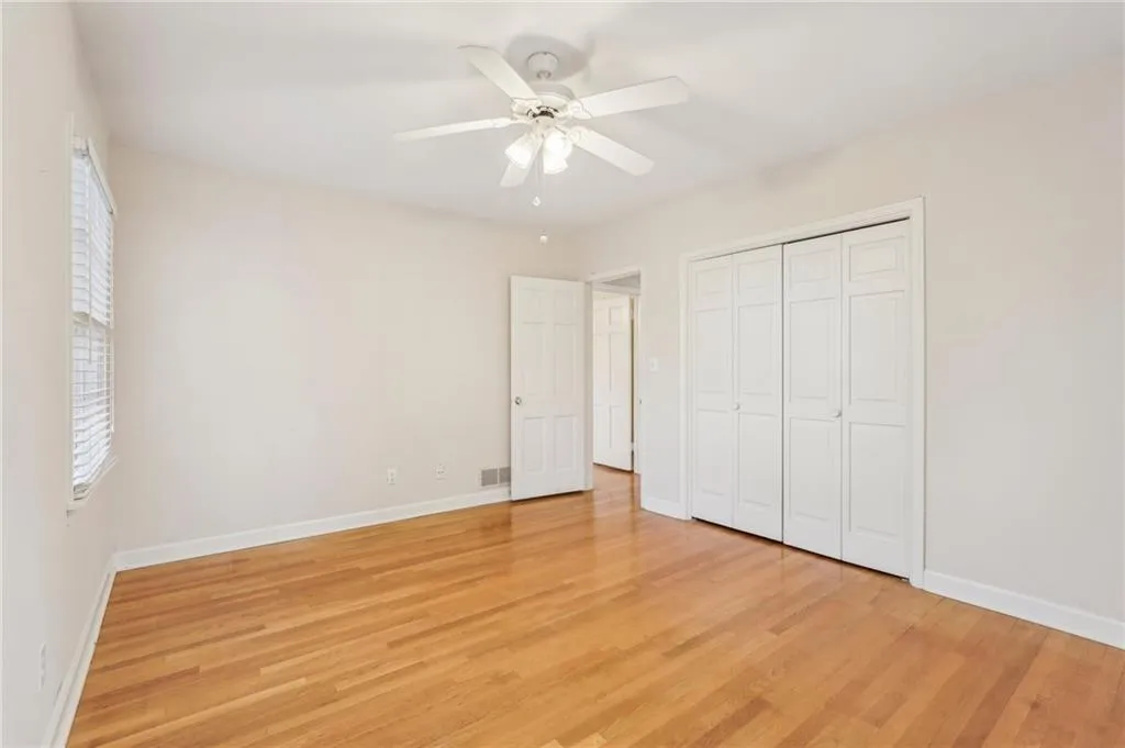Bedroom 3 hardwood flooring, ceiling fan, multiple windows, closet.