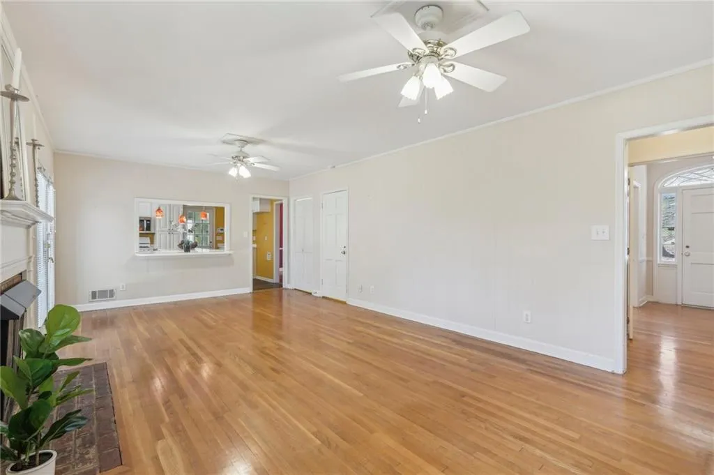Family room with hardwood flooring, ceiling fans, crown molding, and brick fireplace.