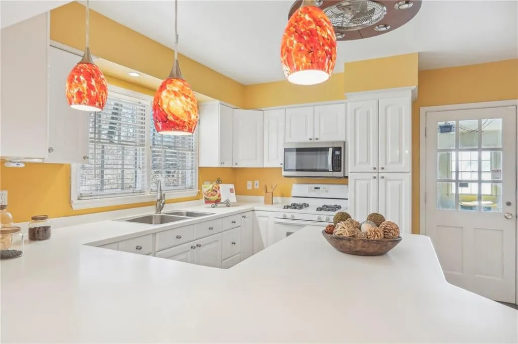 Kitchen featuring white cabinetry, sink, white range with gas cooktop, and pendant lighting