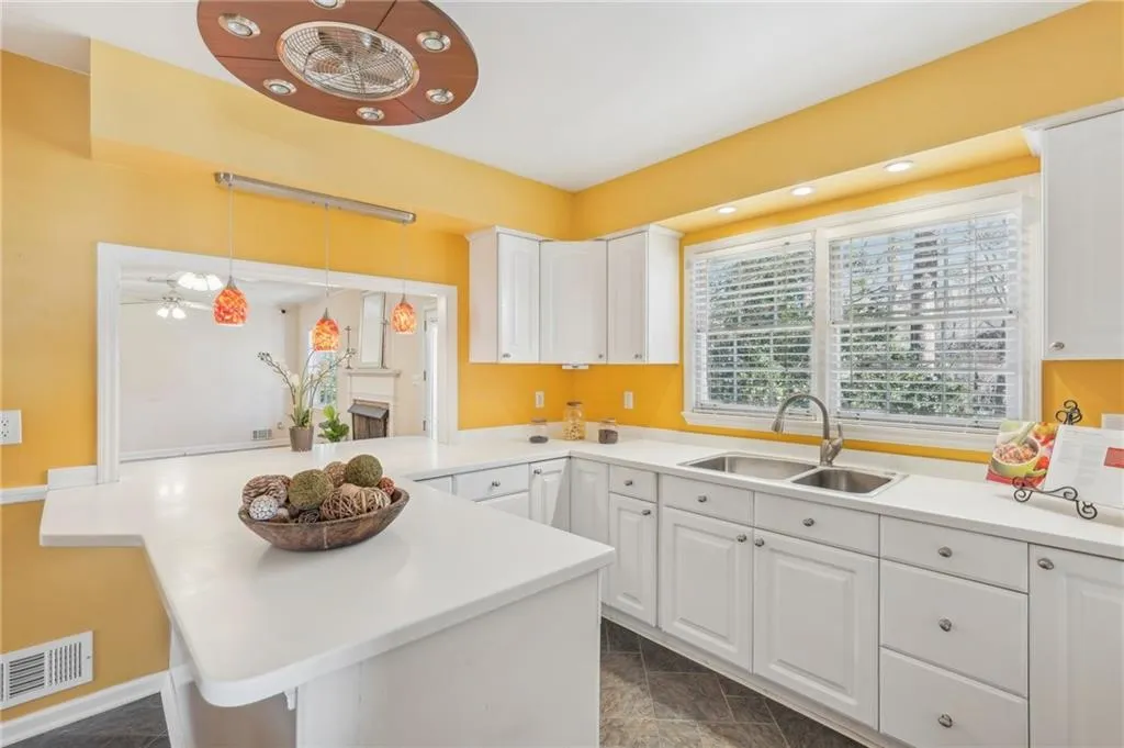 Kitchen with hanging light fixtures, sink, white cabinets, and kitchen peninsula
