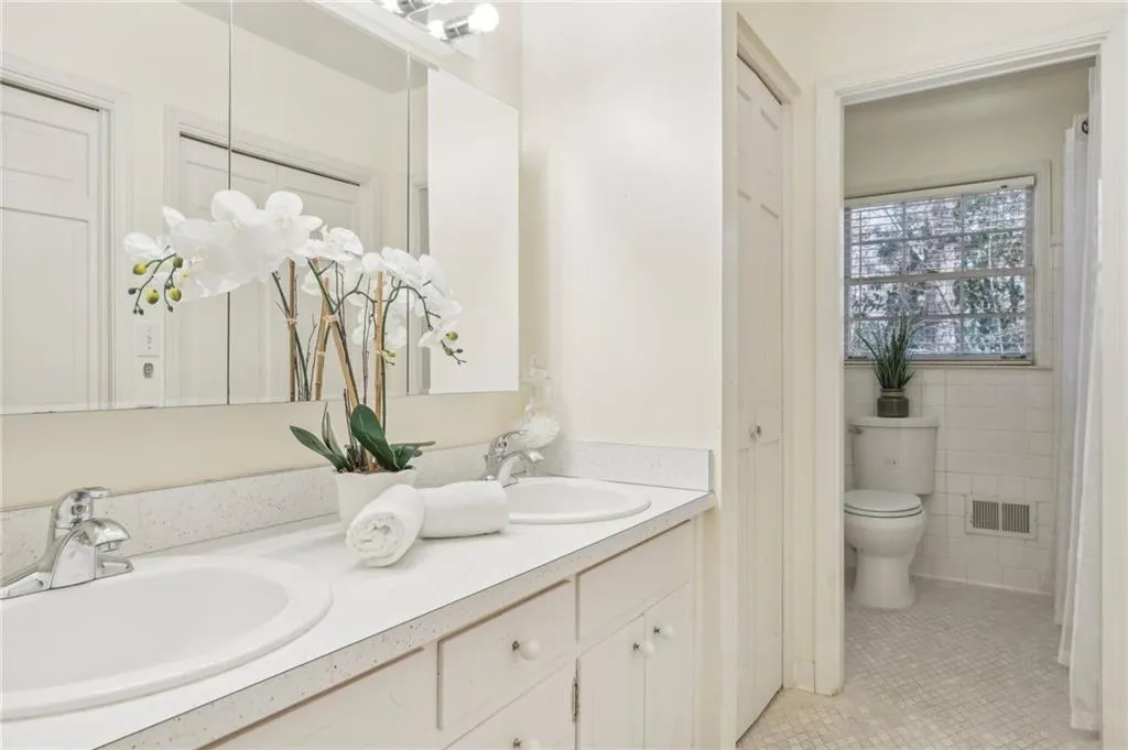 Bathroom featuring twin sinks, vanity, tile patterned flooring, tile walls.