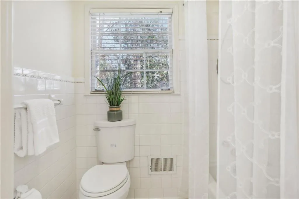 Bathroom featuring toilet, tile walls, and walk in shower