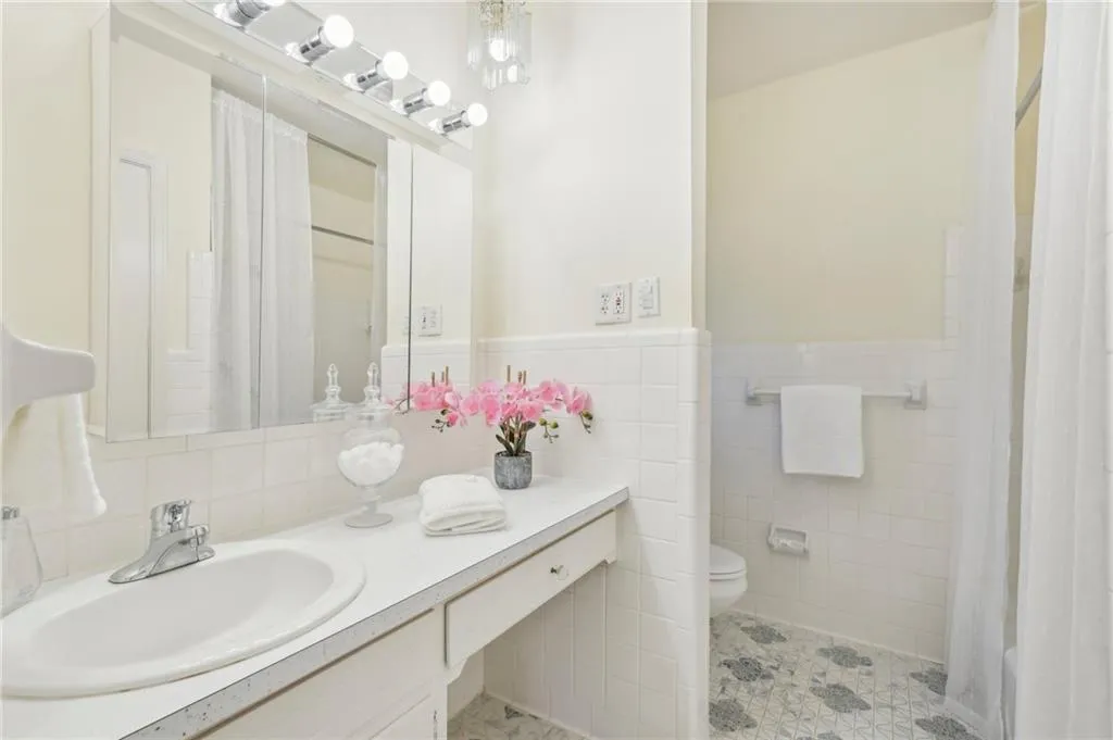 Bathroom with tile walls, vanity, toilet, and curtained shower