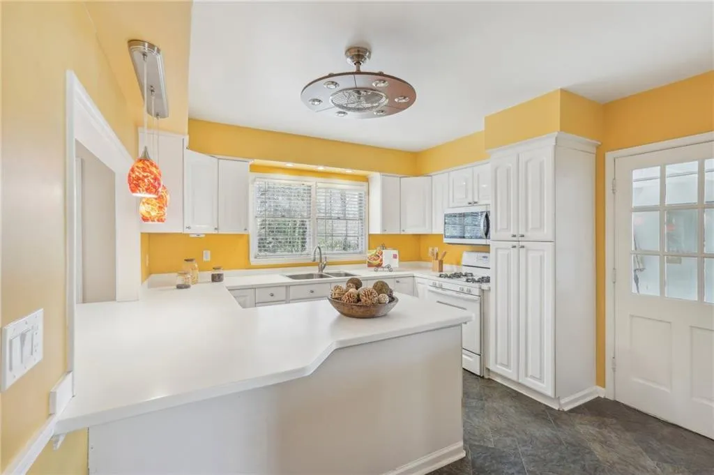 Kitchen featuring decorative light fixtures, white cabinetry, white range with gas cooktop, and kitchen peninsula