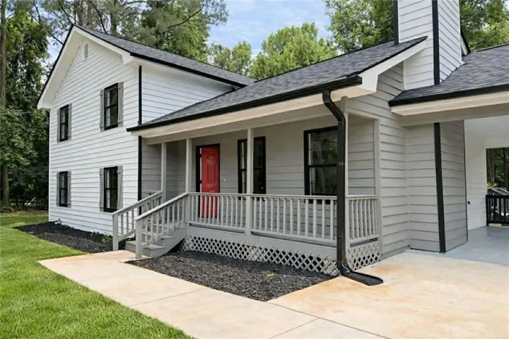 Light gray siding exterior with black-framed windows and a vibrant red entry door
