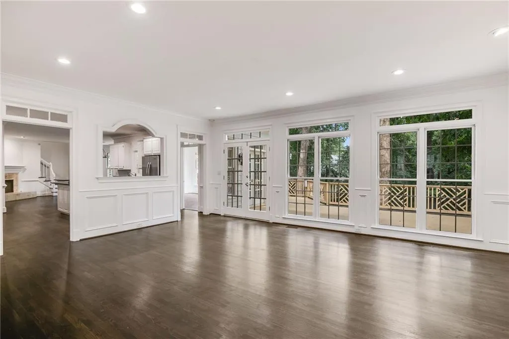 Unfurnished living room with dark wood finished floors, crown molding, a decorative wall, recessed lighting, and a fireplace with raised hearth