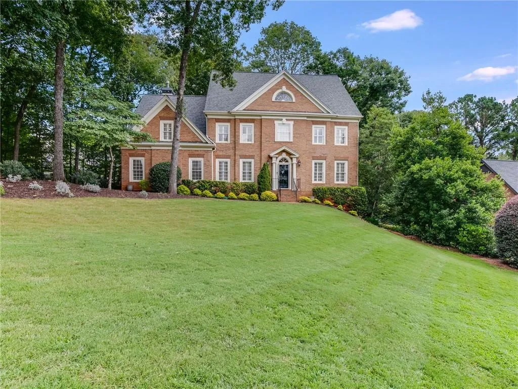 View of front facade featuring a front lawn, brick siding, and a shingled roof