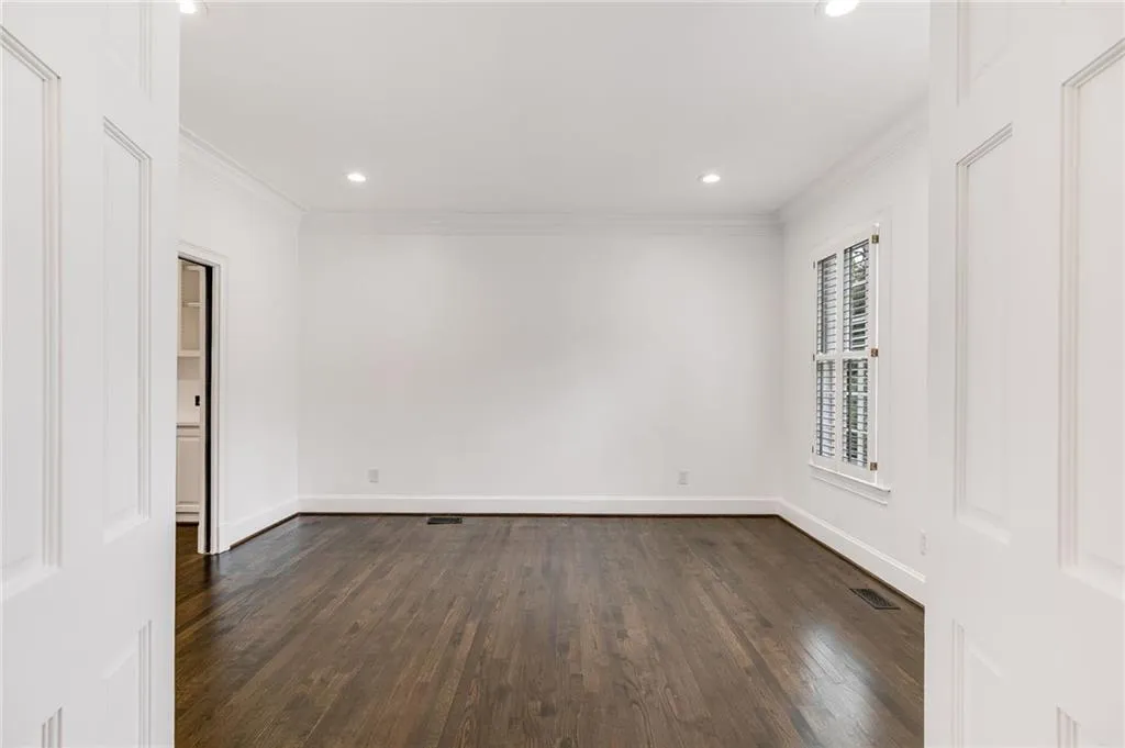 Spare room with dark wood-type flooring, crown molding, and recessed lighting