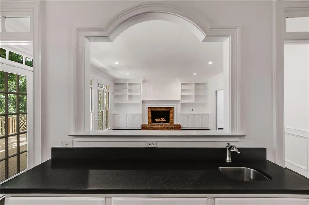 Kitchen with dark stone counters, white cabinetry, built in shelves, and a fireplace