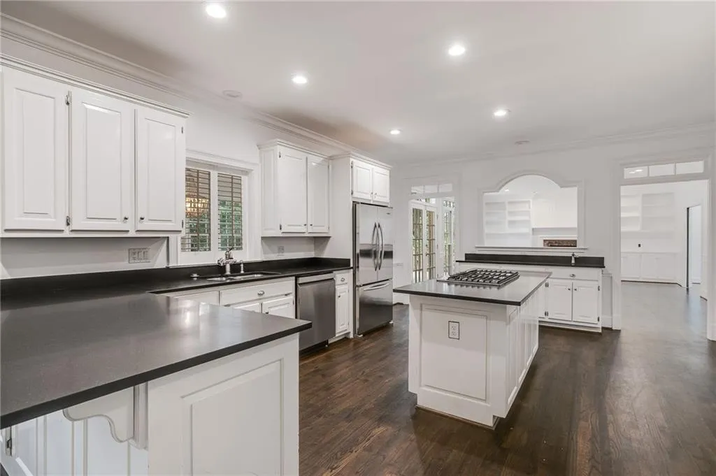 Kitchen featuring a peninsula, a center island, crown molding, dark wood-style floors, and dark countertops