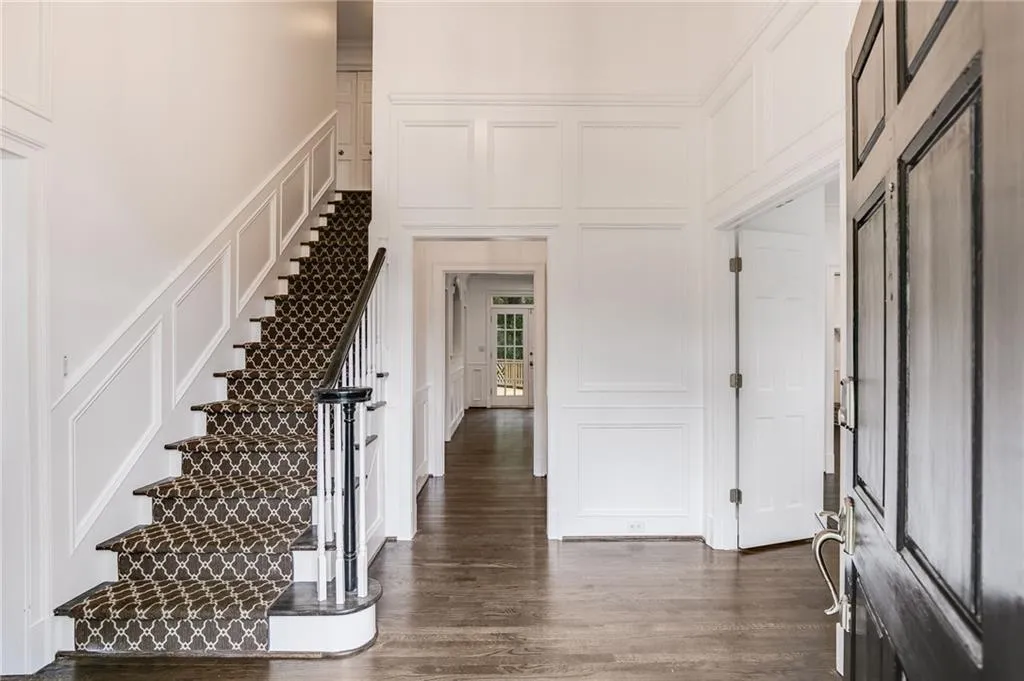 Foyer with a decorative wall, dark wood-style floors, and stairway
