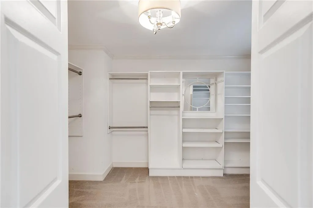 Spacious closet featuring light colored carpet and a chandelier