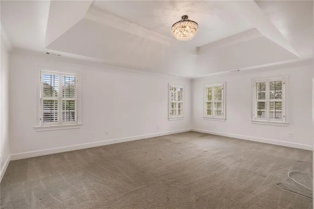 Spare room with a raised ceiling, crown molding, healthy amount of natural light, and light colored carpet
