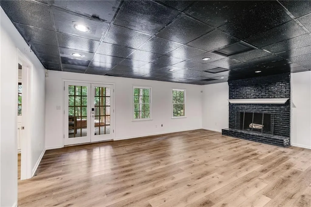Unfurnished living room with light wood finished floors, a fireplace, and french doors