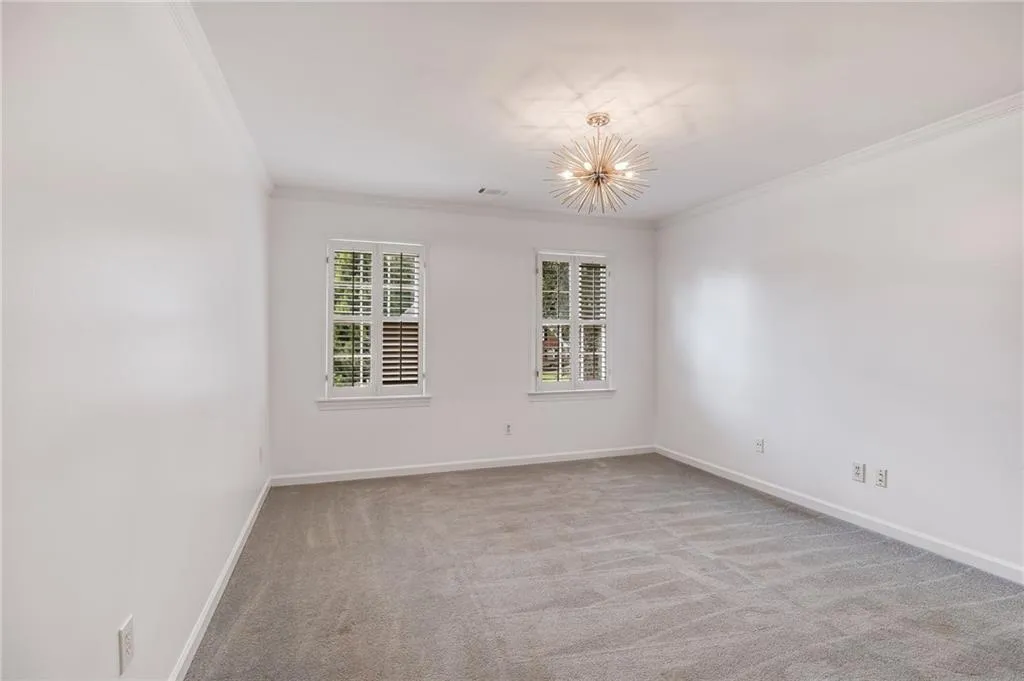 Spare room featuring light carpet, ornamental molding, and a chandelier